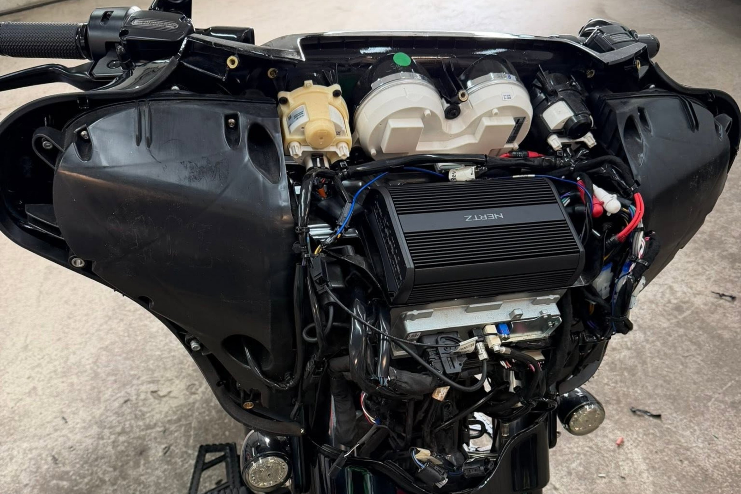 Amp in real on-bike compartment, wiring routing visible — installed by Sturgess Customs