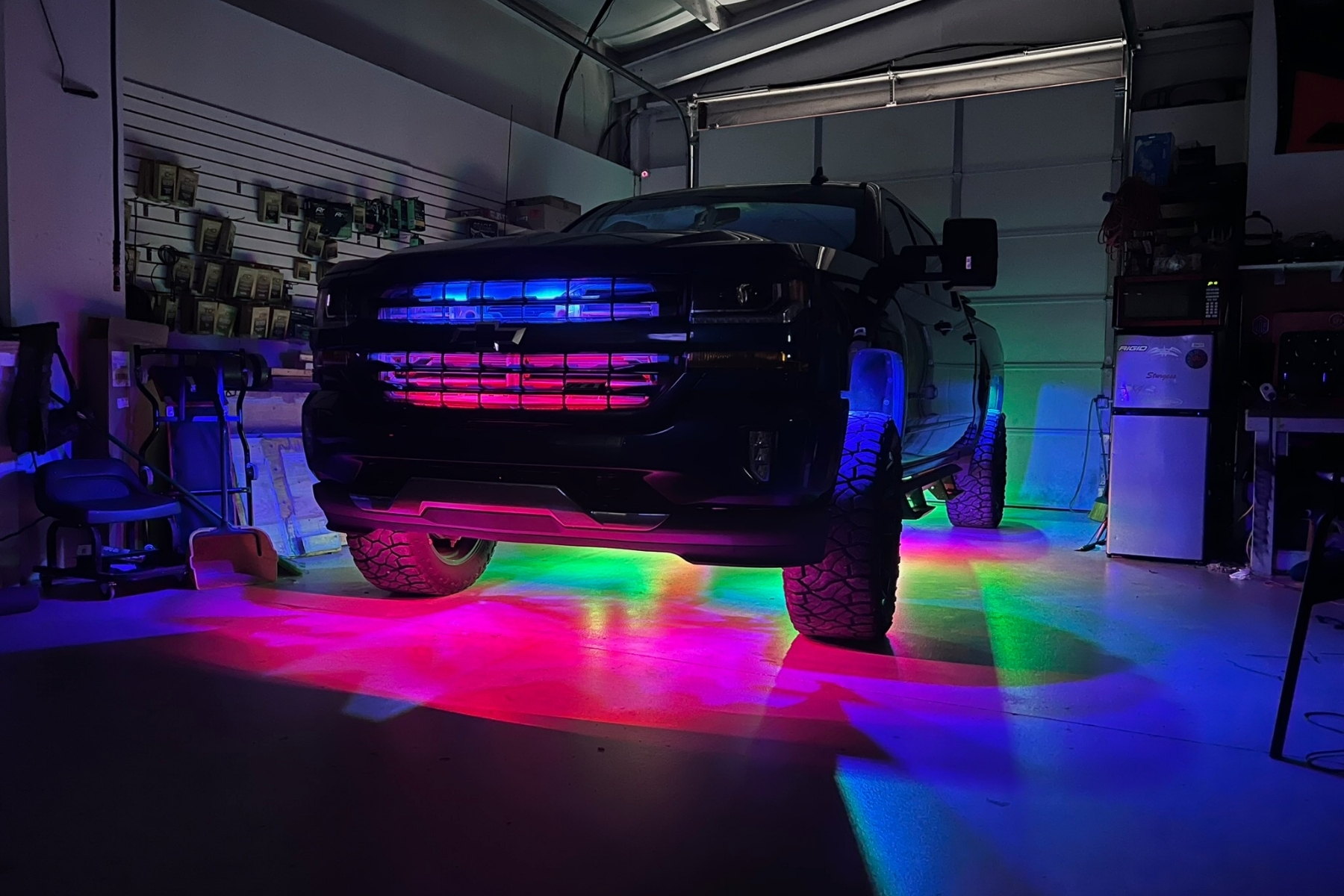 Exterior underglow and rock lighting on a lifted truck in the shop — installed by Sturgess Customs